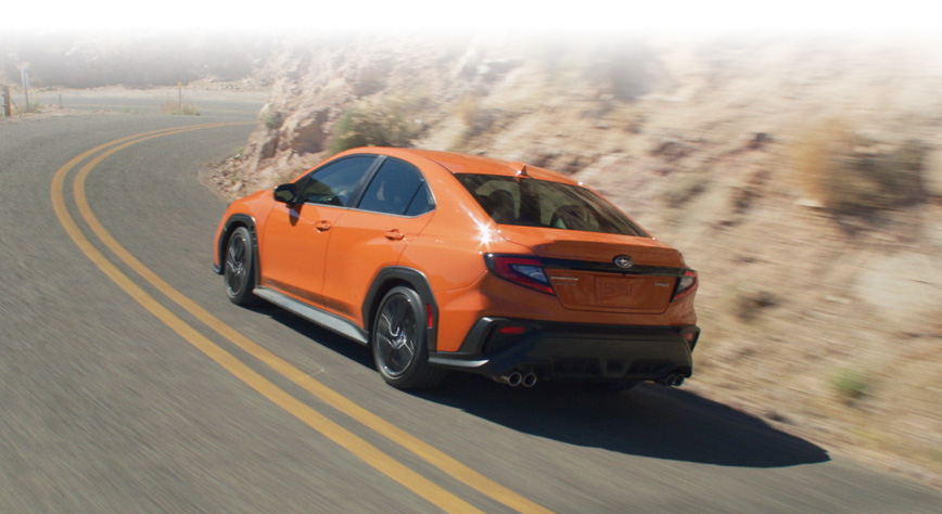 Rear shot of 2023 WRX Sport-tech driving on mountain road.