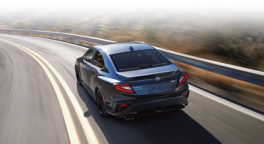 Rear shot of 2024 WRX Sport-tech driving on mountain road.