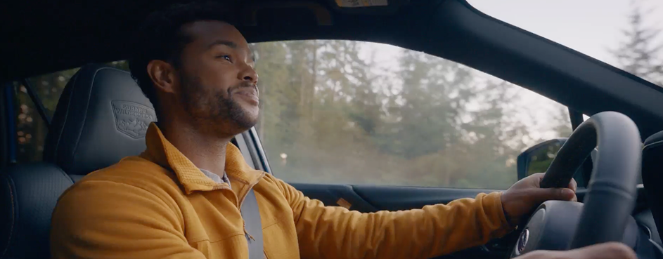 Un homme conduisant une voiture, les mains sur le volant, concentré sur la route devant lui