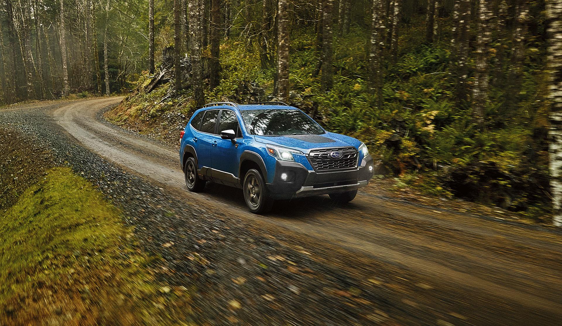 Front shot of 2023 Forester Wilderness driving on a forest trail.