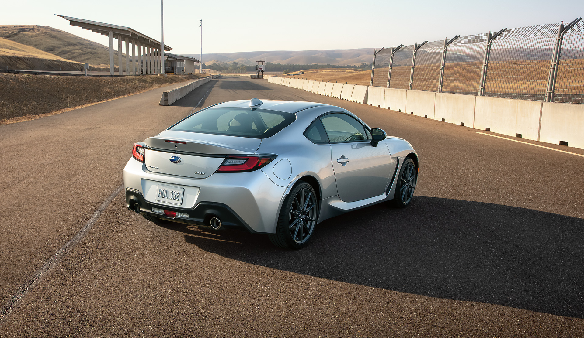 Vue arrière de la BRZ 2024 immobilisée près de la clôture d’une piste de course.