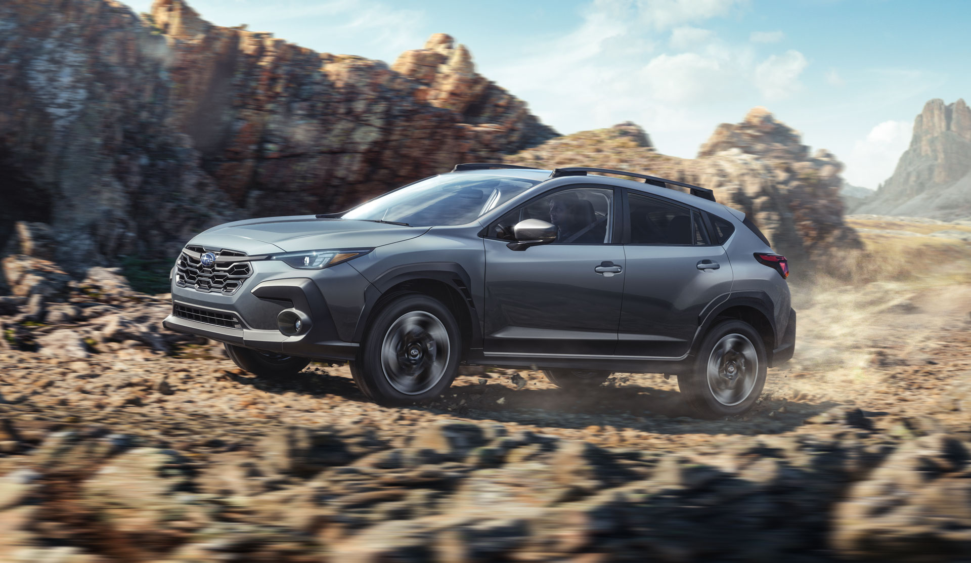 2024 Crosstrek racing up a dusty canyon road.