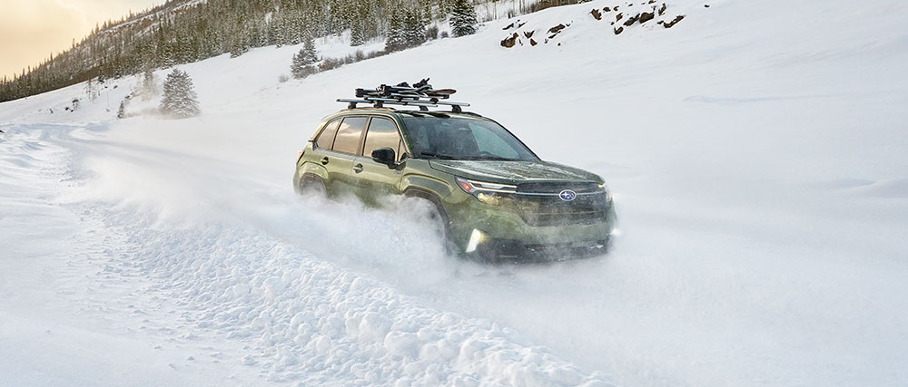 2026 Subaru Forester Hybrid Premier driving through a snowy winter landscape.