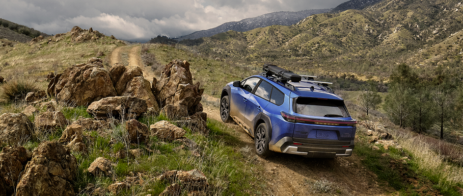 Un modèle VÉ Subaru bleu circulant sur un chemin de terre bordé d’arbres.