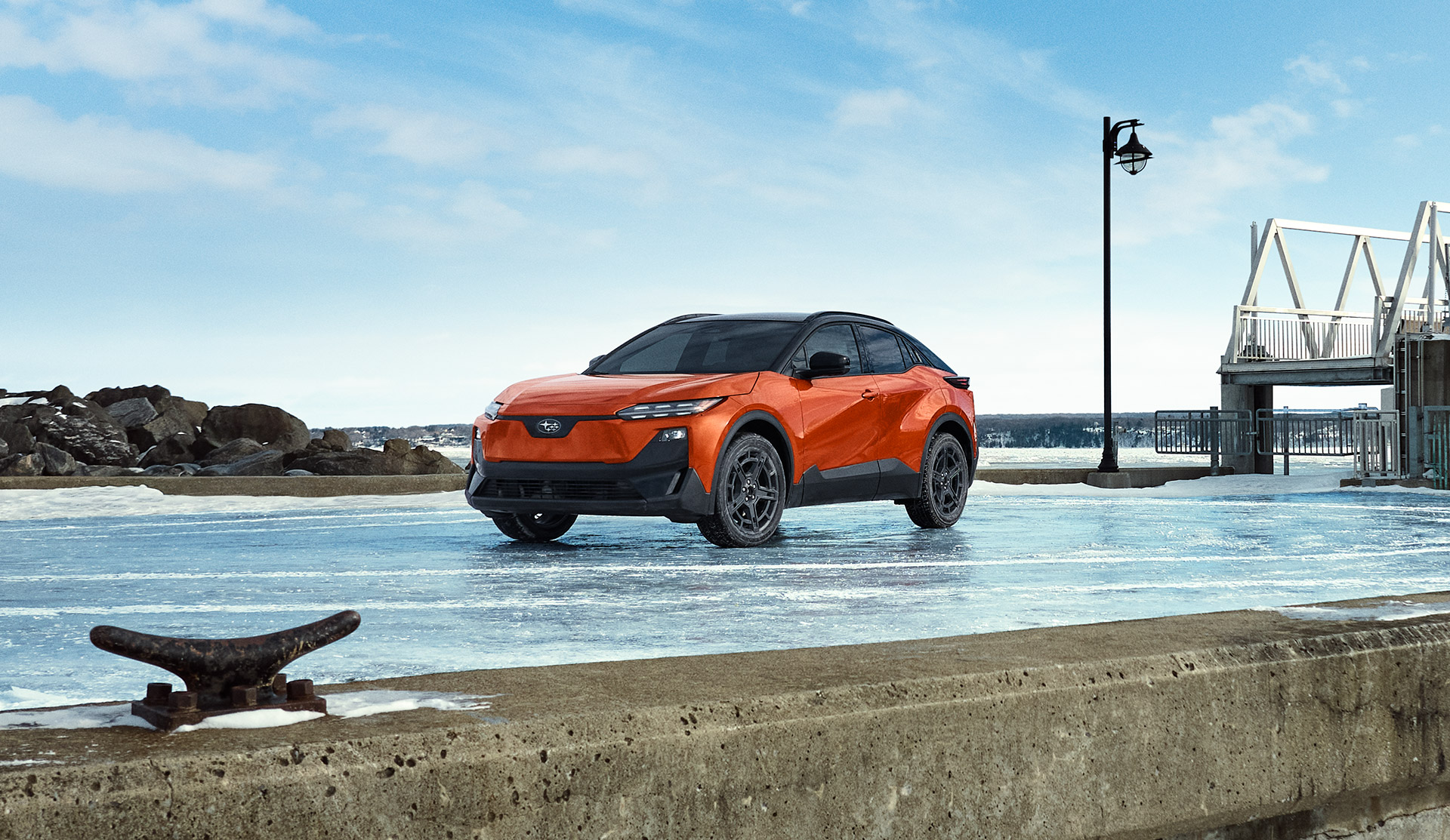 2026 Subaru parked on an icy surface near a waterfront with rocks, water, and a modern pier structure in the background 